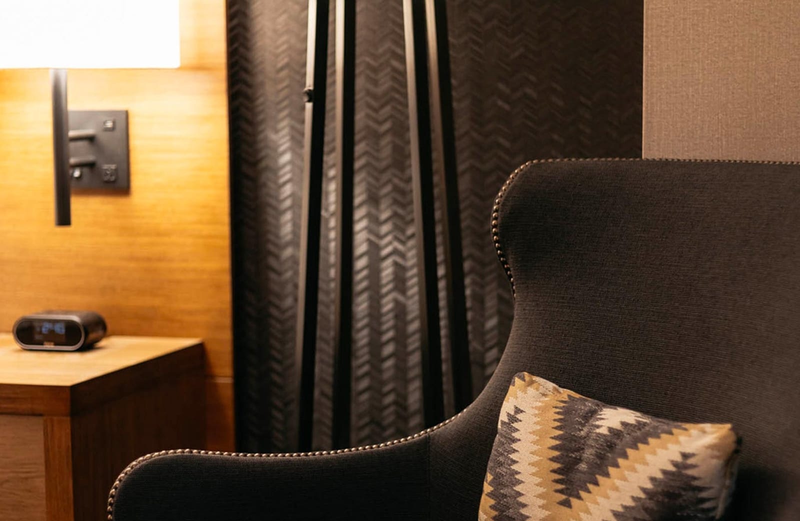 A brown cloth chair with a native american patterned pillow